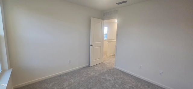 carpeted empty room featuring visible vents and baseboards