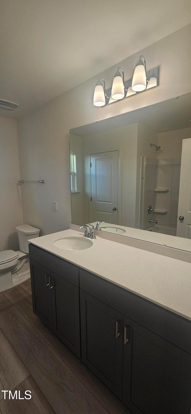 full bathroom with bathing tub / shower combination, vanity, toilet, and wood finished floors