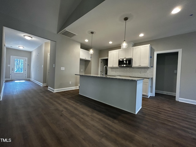 kitchen with white cabinetry, visible vents, dark wood-style floors, and stainless steel microwave