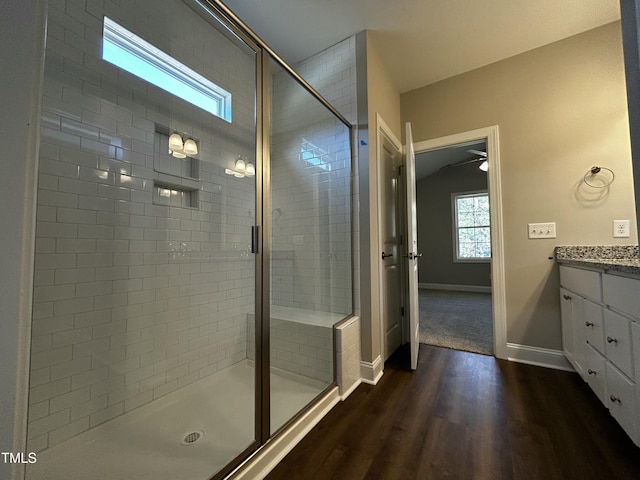 full bath featuring a shower stall, baseboards, wood finished floors, and vanity