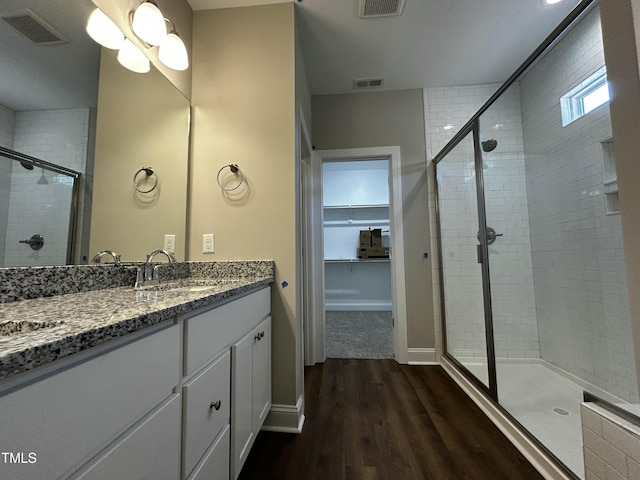 bathroom with a shower stall, visible vents, wood finished floors, and vanity