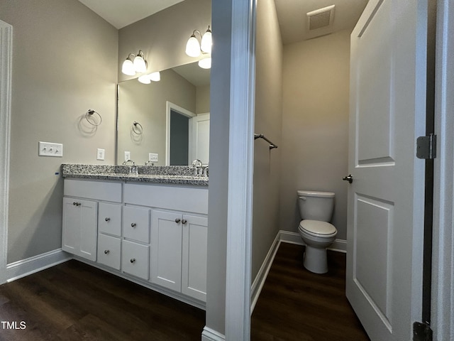 bathroom featuring double vanity, wood finished floors, visible vents, and baseboards