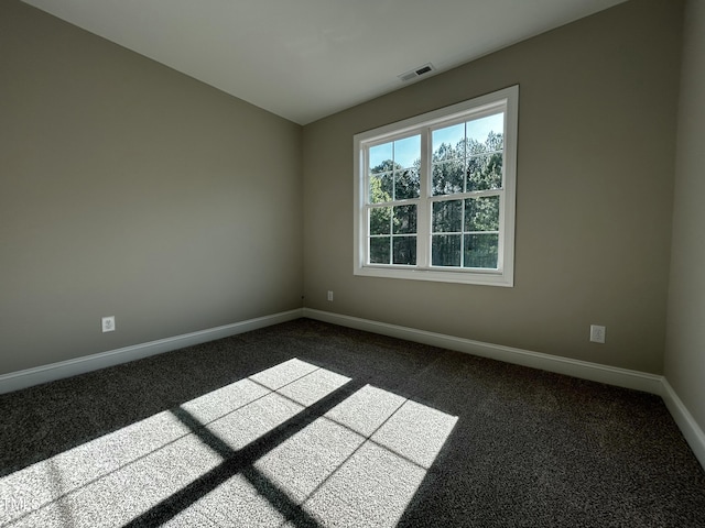 spare room with visible vents, dark carpet, and baseboards