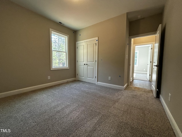 unfurnished bedroom featuring baseboards, multiple windows, and carpet flooring