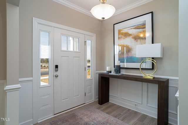 entryway with a wainscoted wall, wood finished floors, and crown molding