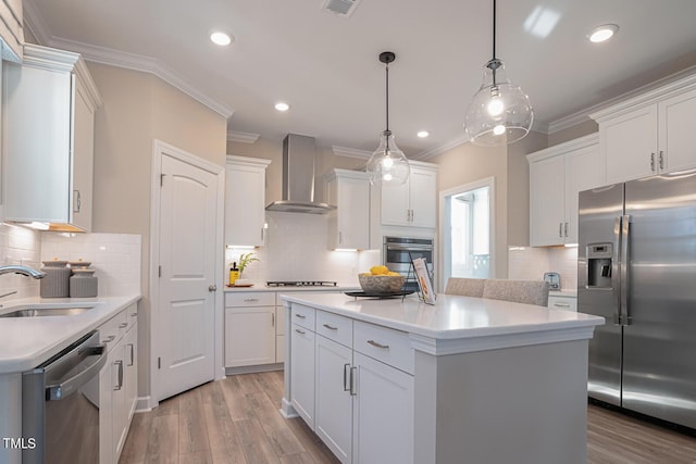 kitchen with white cabinets, wall chimney range hood, stainless steel appliances, and light countertops