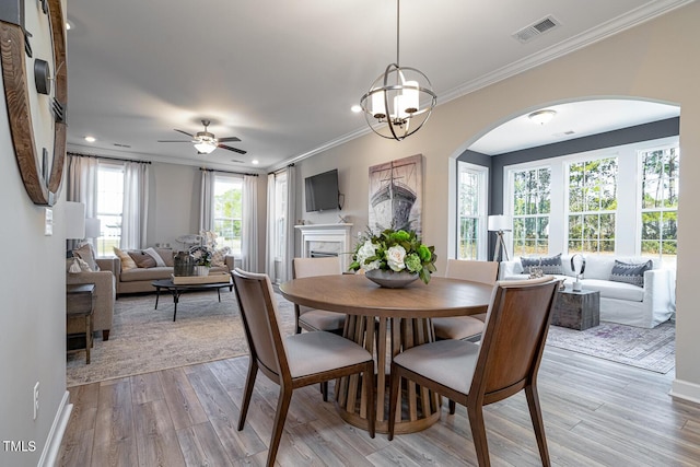 dining space featuring arched walkways, crown molding, recessed lighting, visible vents, and light wood-type flooring