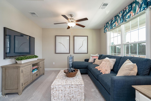 living area featuring baseboards, ceiling fan, visible vents, and light colored carpet