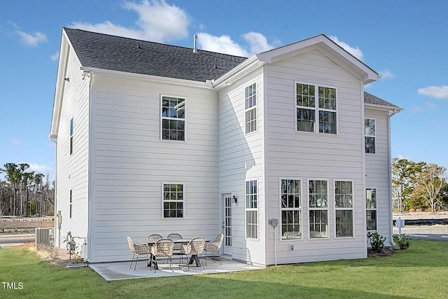 rear view of property featuring central air condition unit, a patio area, a lawn, and roof with shingles