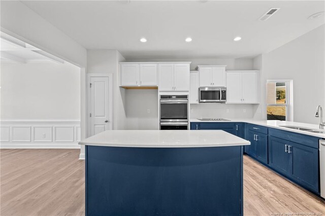 kitchen featuring blue cabinetry, appliances with stainless steel finishes, white cabinetry, and sink