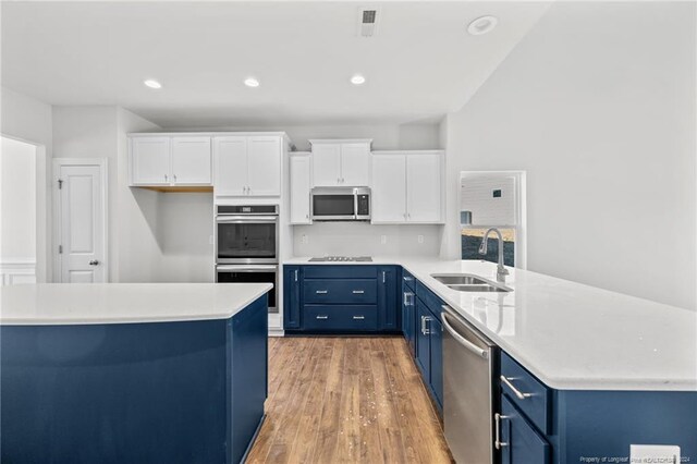 kitchen featuring blue cabinetry, appliances with stainless steel finishes, white cabinetry, and sink