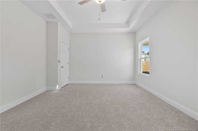 unfurnished room featuring ceiling fan, a raised ceiling, and light colored carpet