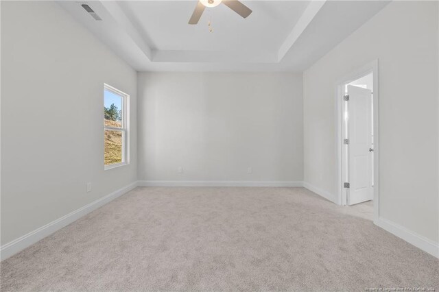 carpeted spare room with ceiling fan and a tray ceiling