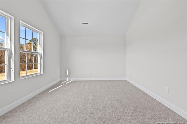 carpeted spare room with lofted ceiling