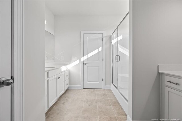 bathroom featuring tile patterned floors, a shower with door, and vanity