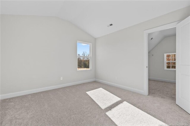 empty room with light colored carpet and vaulted ceiling