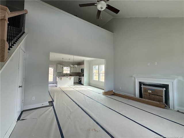 unfurnished living room featuring a fireplace, plenty of natural light, high vaulted ceiling, and ceiling fan