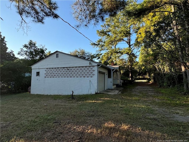 view of side of property with a lawn, an attached garage, and concrete block siding