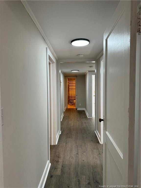 hall with dark wood-style floors, ornamental molding, and baseboards