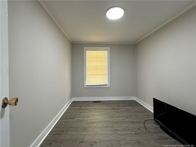 spare room featuring dark wood-style flooring, crown molding, and baseboards