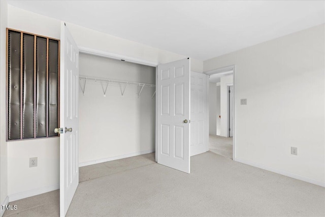 unfurnished bedroom with a closet and light colored carpet