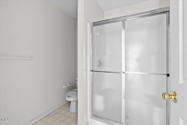 bathroom featuring toilet and a shower with shower door