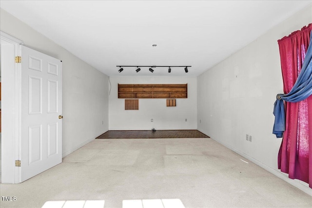 empty room with light colored carpet and track lighting