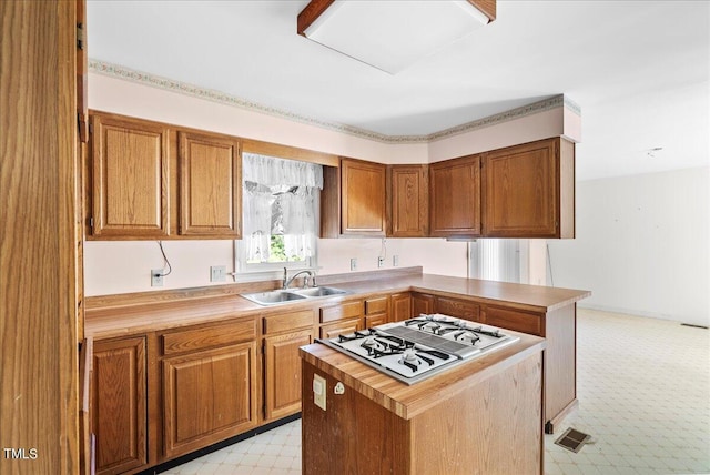 kitchen featuring a center island, white gas cooktop, sink, and light carpet