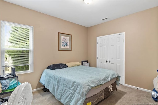 bedroom featuring light carpet, a closet, and multiple windows