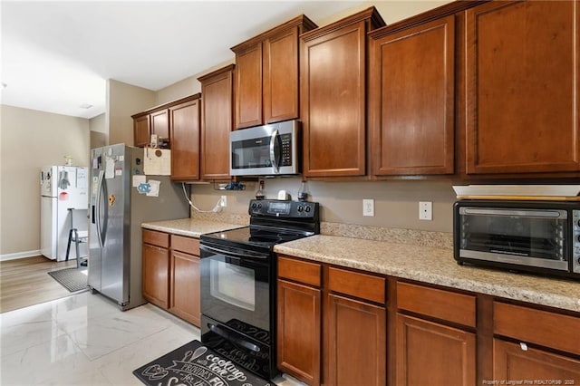 kitchen with a toaster, baseboards, marble finish floor, appliances with stainless steel finishes, and brown cabinetry