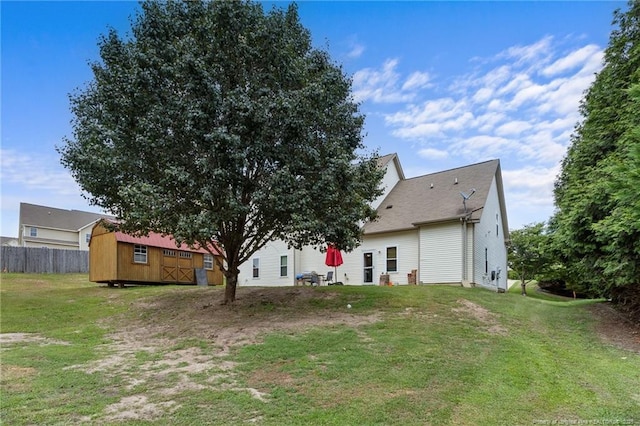 rear view of property with a storage shed, fence, an outdoor structure, and a yard