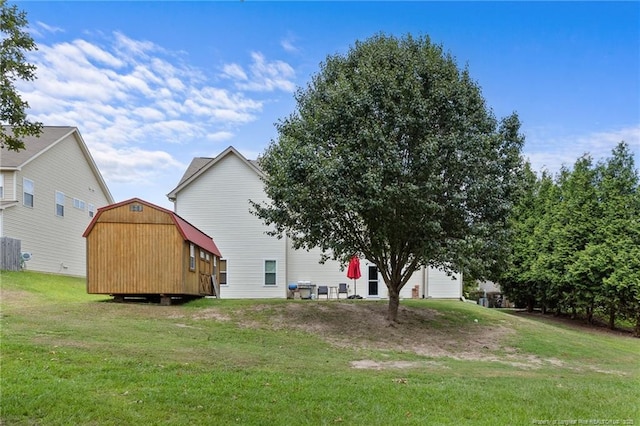 rear view of property featuring a storage unit, an outbuilding, and a yard