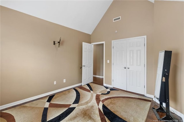 bedroom featuring high vaulted ceiling, a closet, visible vents, and baseboards