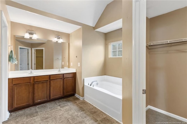 bathroom with a walk in closet, a garden tub, a sink, and double vanity