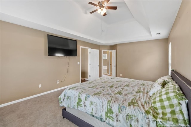 carpeted bedroom featuring a ceiling fan, a tray ceiling, and baseboards