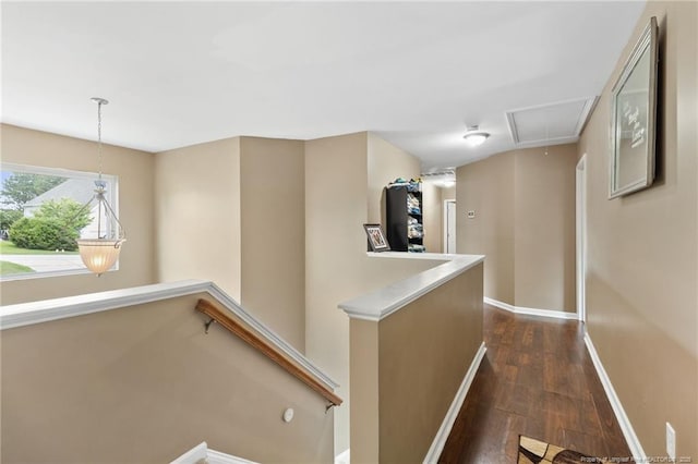 corridor featuring dark wood-style flooring, an upstairs landing, attic access, and baseboards