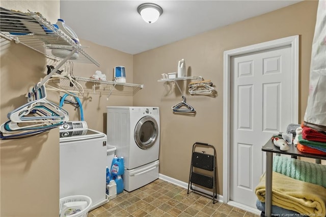 washroom with laundry area, washing machine and dryer, and baseboards