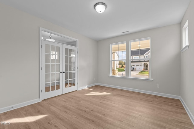 unfurnished room with french doors and light hardwood / wood-style flooring