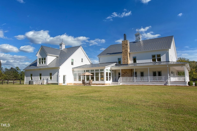 rear view of house featuring a lawn and covered porch