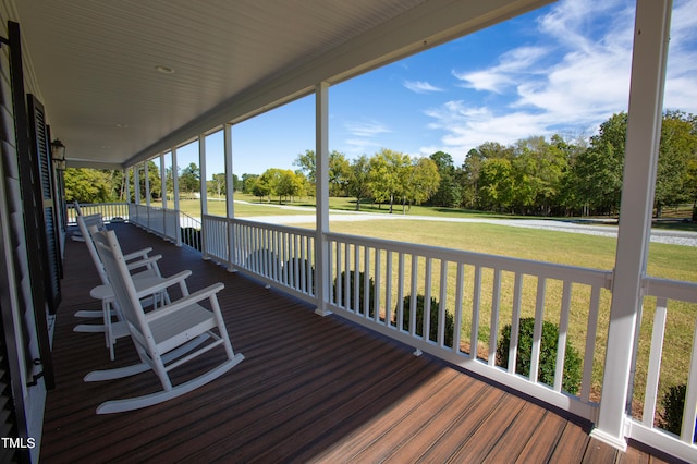 wooden terrace with a porch and a lawn