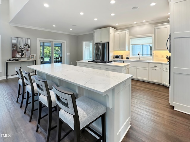 kitchen featuring stainless steel appliances, white cabinets, dark hardwood / wood-style flooring, and a center island