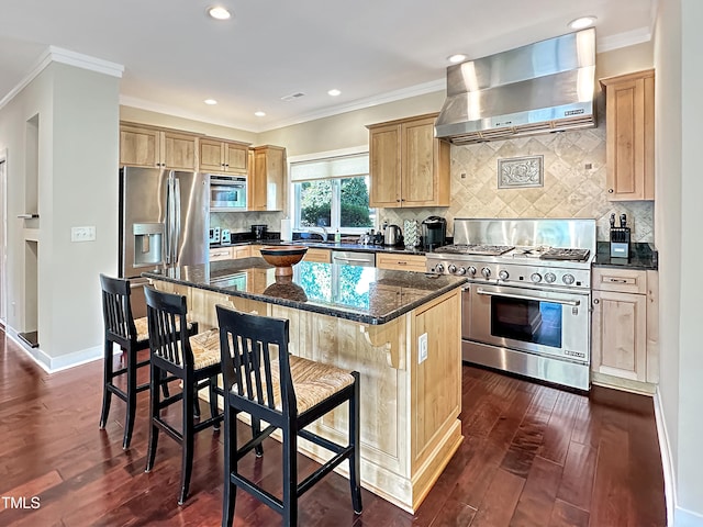 kitchen with wall chimney range hood, appliances with stainless steel finishes, a center island, and dark hardwood / wood-style flooring