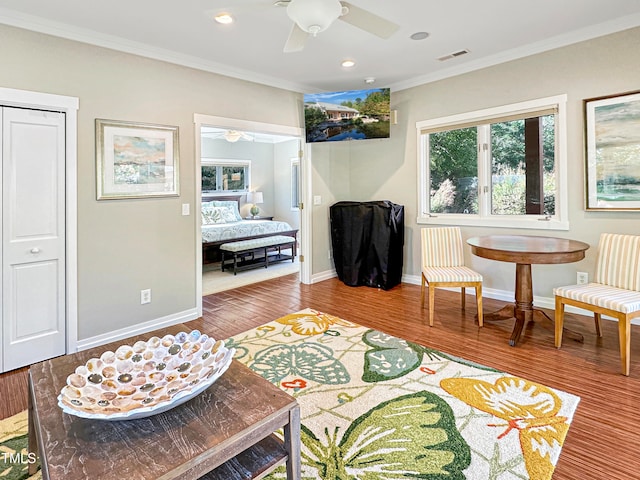 sitting room with hardwood / wood-style flooring, crown molding, and ceiling fan