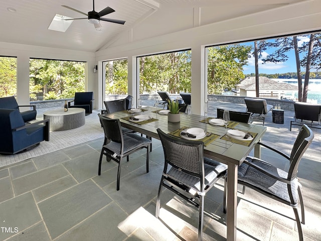 sunroom featuring ceiling fan, a healthy amount of sunlight, a water view, and lofted ceiling with skylight