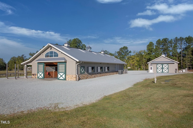 view of front of house with central air condition unit, a front yard, and an outdoor structure