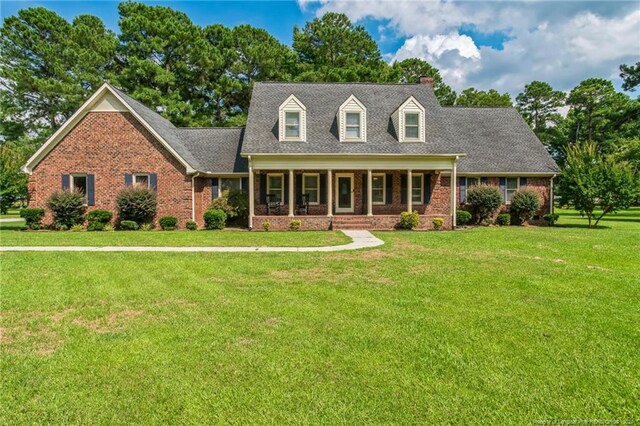 cape cod home with covered porch and a front yard