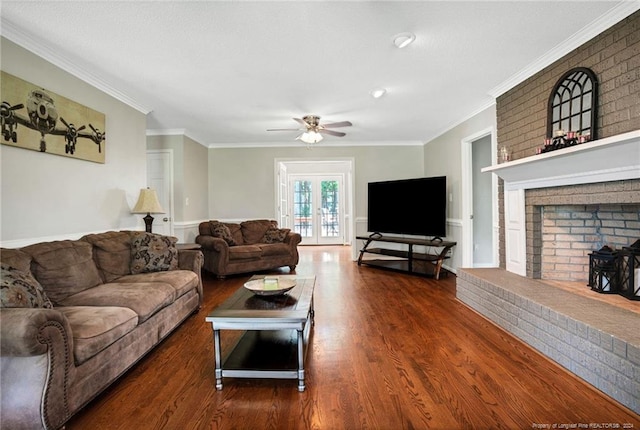 living room with a fireplace, ceiling fan, crown molding, french doors, and dark wood-type flooring