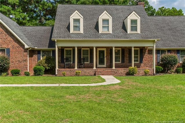 new england style home featuring covered porch and a front yard