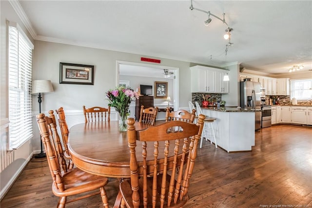 dining room featuring crown molding, dark hardwood / wood-style flooring, and track lighting