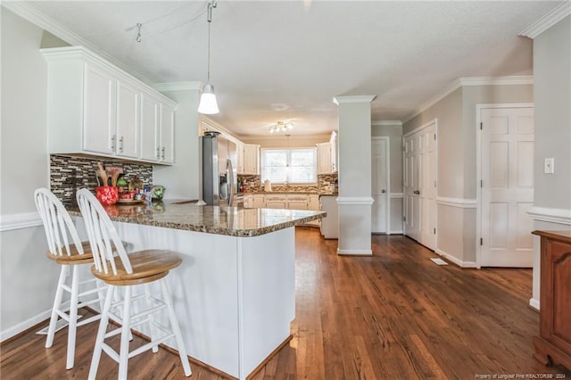 kitchen featuring decorative backsplash, pendant lighting, stainless steel fridge, and white cabinetry